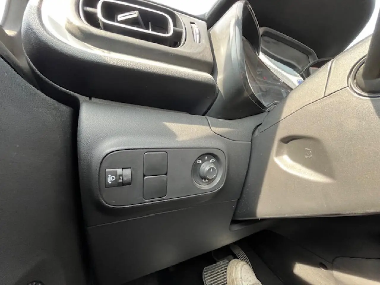 Détail des commandes de réglage des rétroviseurs côté gauche dans l'habitacle noir d'une Citroën C3 2023.