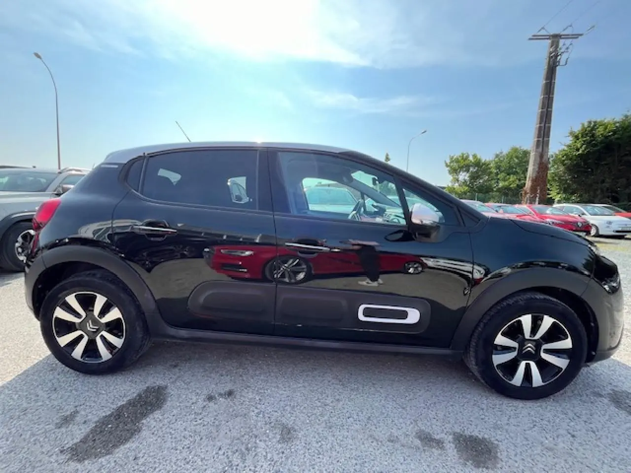 Profil latéral gauche d'une Citroën C3 noire 2023 avec jantes alliage et protections latérales caractéristiques.