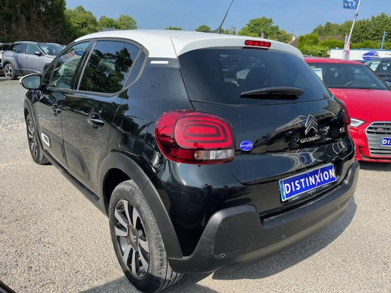 Vue 3/4 arrière gauche d'une Citroën C3 noire avec toit blanc et jantes alliage 16 pouces diamantées.