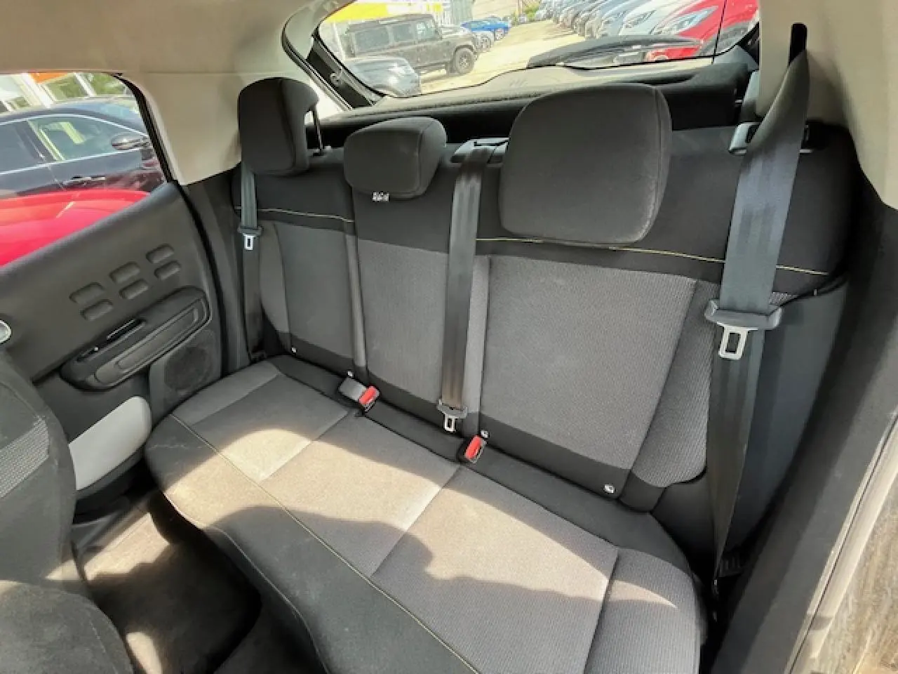 Banquette arrière noire et grise de la Citroën C3 2023, vue de côté droit avec ceintures et appuie-têtes visibles.
