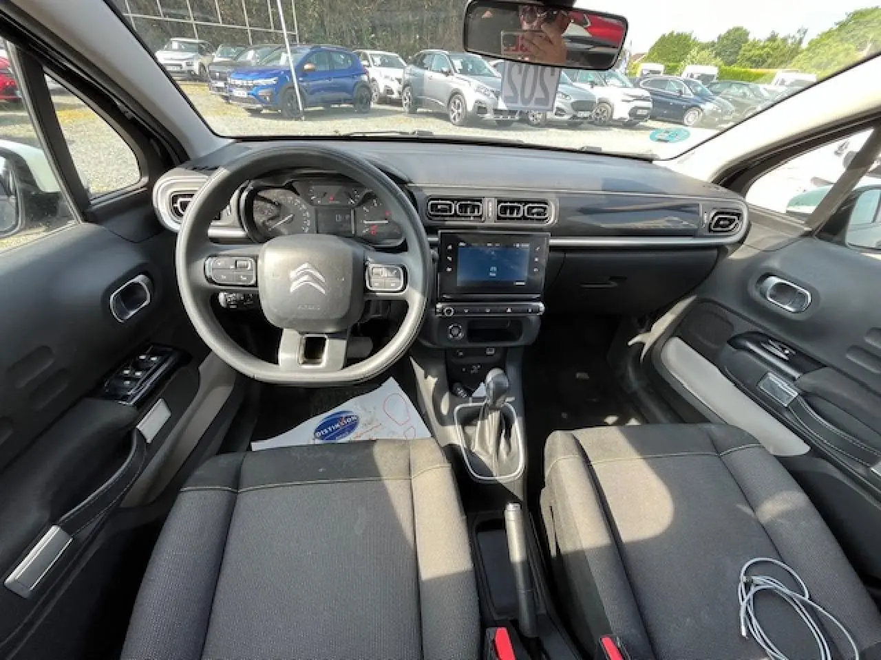 Vue intérieure avant de la Citroën C3 noire 2023, tableau de bord moderne avec écran tactile et volant multifonction.