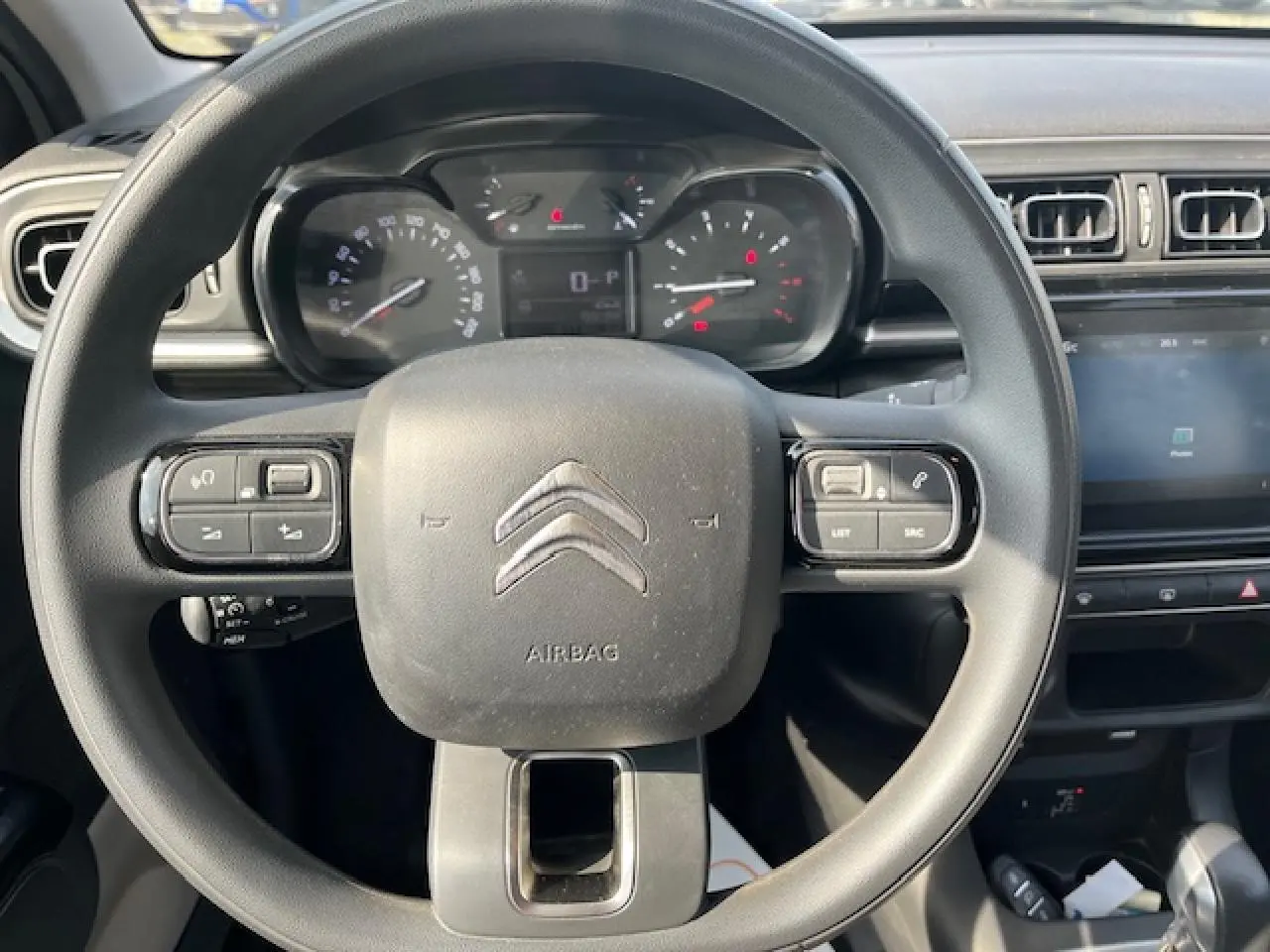 Vue rapprochée du volant noir de la Citroën C3 2023 avec commandes intégrées et tableau de bord digital.