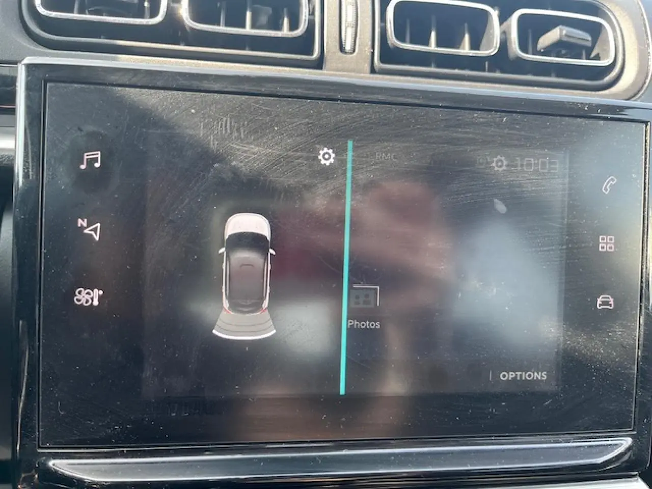 Écran tactile central du tableau de bord d'une Citroën C3 noire 2023 montrant l'aide au stationnement avec vue aérienne du véhicule.