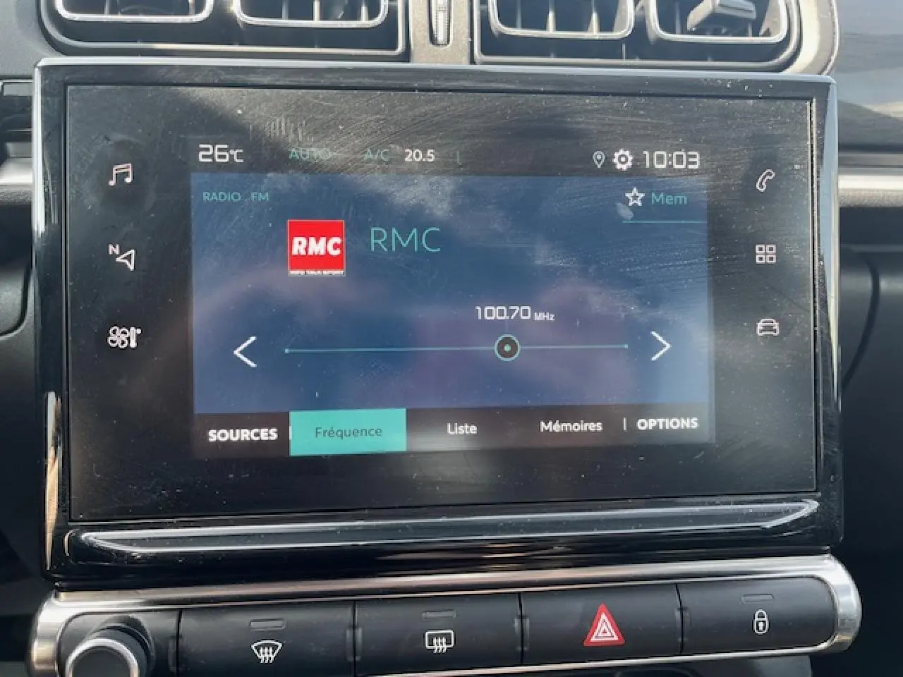Écran tactile central de la Citroën C3 noire 2023 affichant la radio RMC à 100,7 MHz en vue frontale rapprochée.