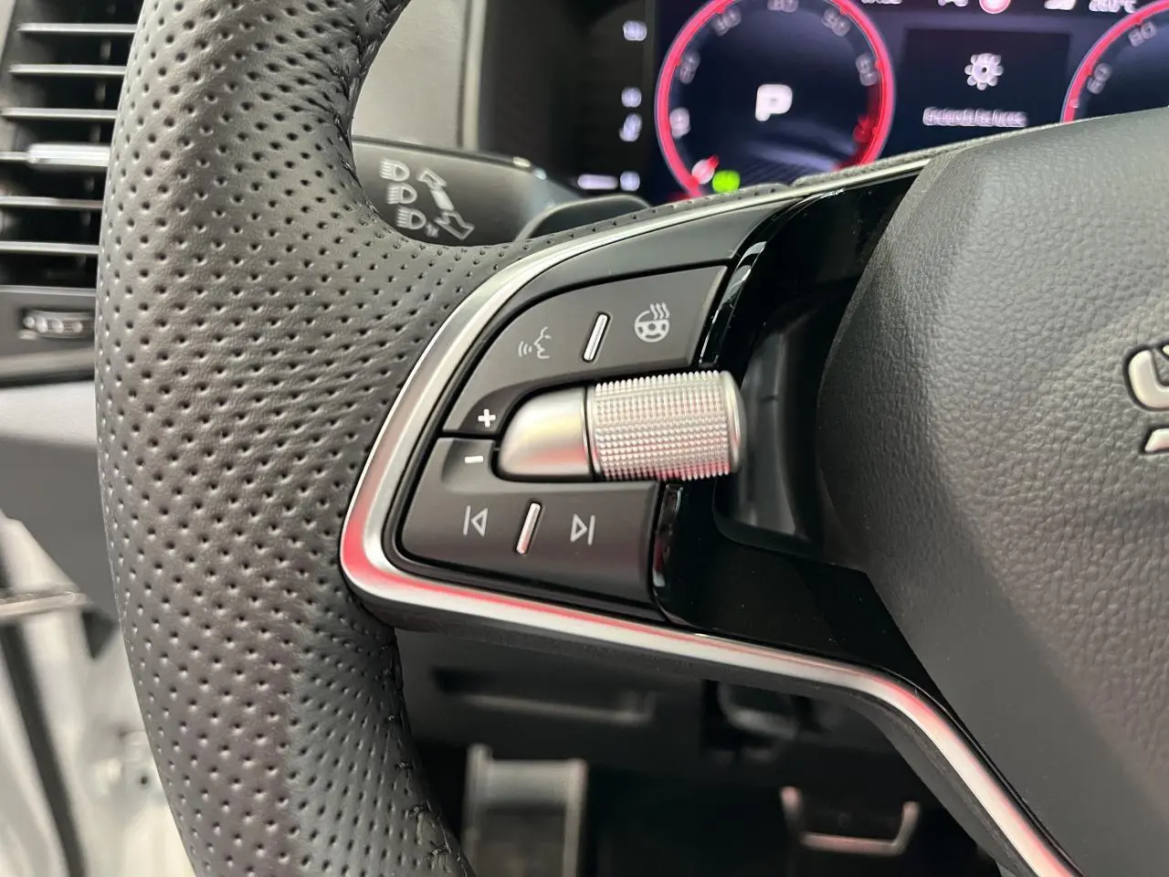 Gros plan sur les commandes du volant cuir perforé noir du Skoda Karoq 2025 avec molette métallique et tableau de bord digital.