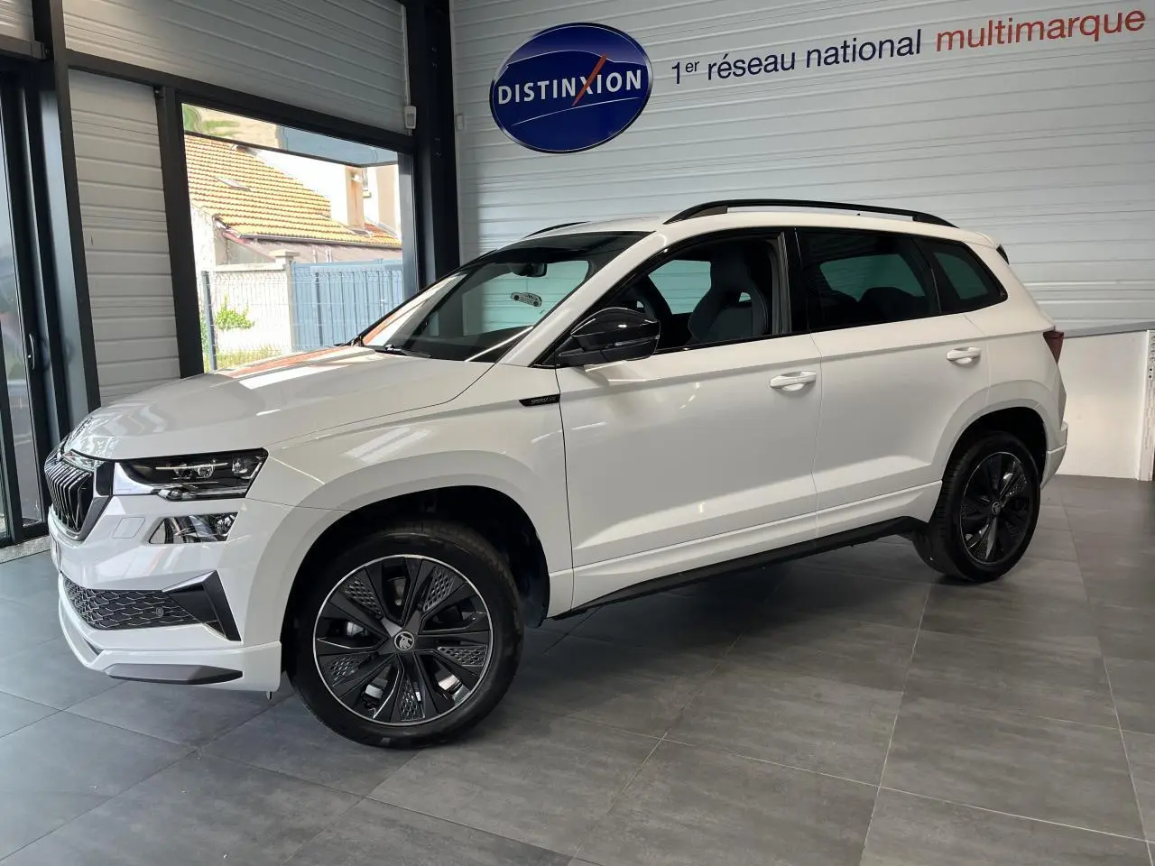 SUV SKODA KAROQ blanc vue de côté droit en intérieur avec jantes noires et toit noir Sportline