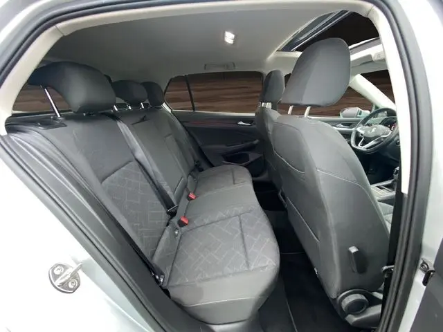 Vue intérieure côté gauche montrant la banquette arrière et le toit panoramique ouvrant d'une Volkswagen Golf VIII gris argent.