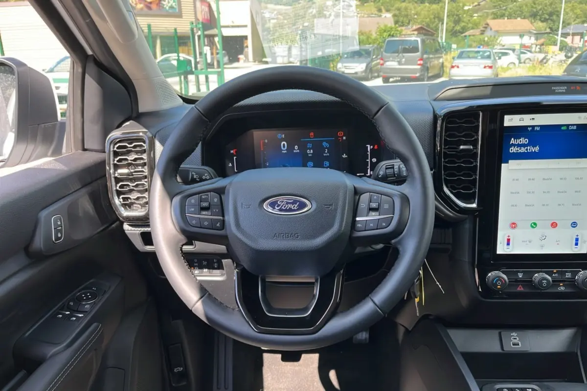 Vue intérieure du tableau de bord du Ford Ranger 2025, volant multifonction et écran tactile central avec interface désactivée.