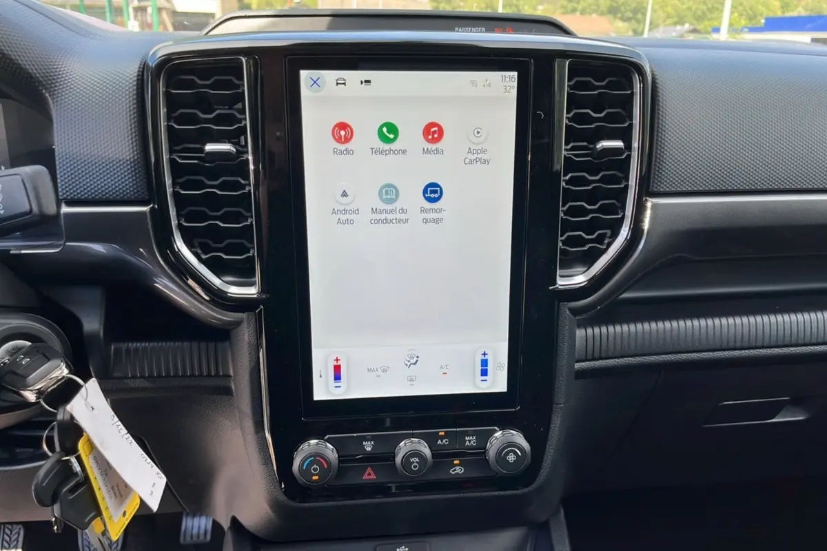Vue rapprochée de la console centrale tactile du Ford Ranger blanc glacier 2025 avec commandes climatisation et connectivité Apple CarPlay.