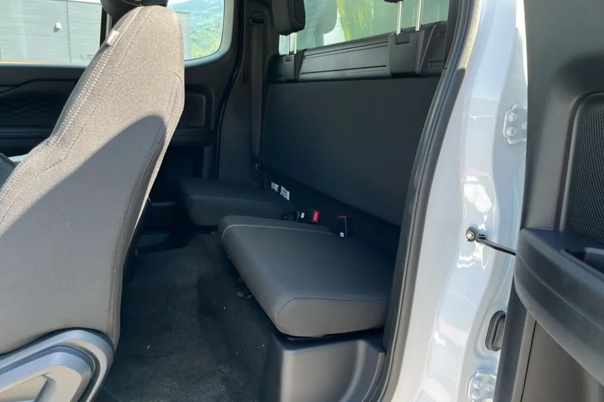 Vue intérieure côté droit du Ford Ranger 2025 blanc glacier, montrant la banquette arrière compacte et les sièges avant en tissu noir.