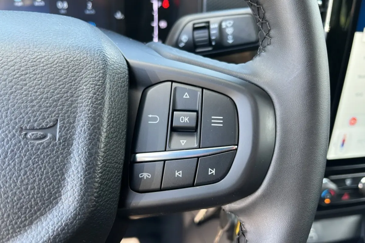 Gros plan sur les commandes multifonctions à droite du volant du Ford Ranger blanc glacier 2025, version XLT SuperCab.