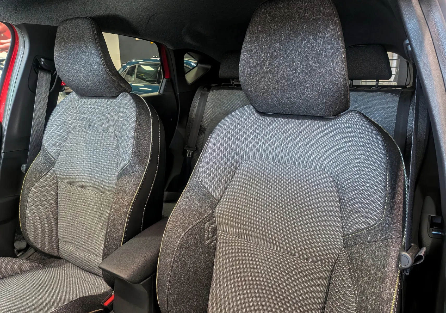 Gros plan sur les sièges avant en tissu gris du Renault Captur E-TECH 2025, intérieur visible côté gauche.