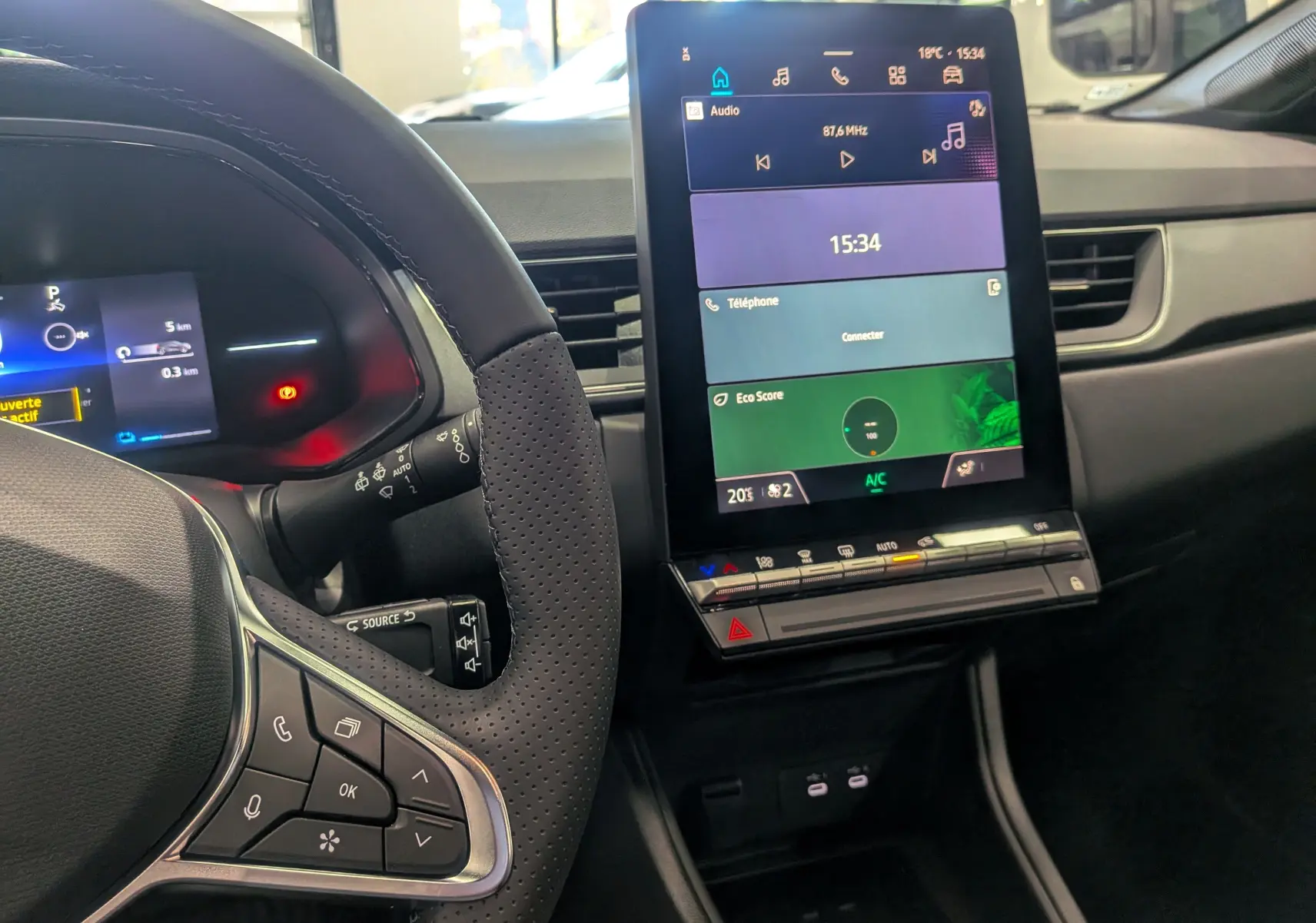 Vue intérieure du tableau de bord et volant du Renault Captur E-TECH 2025 avec écran tactile central allumé.