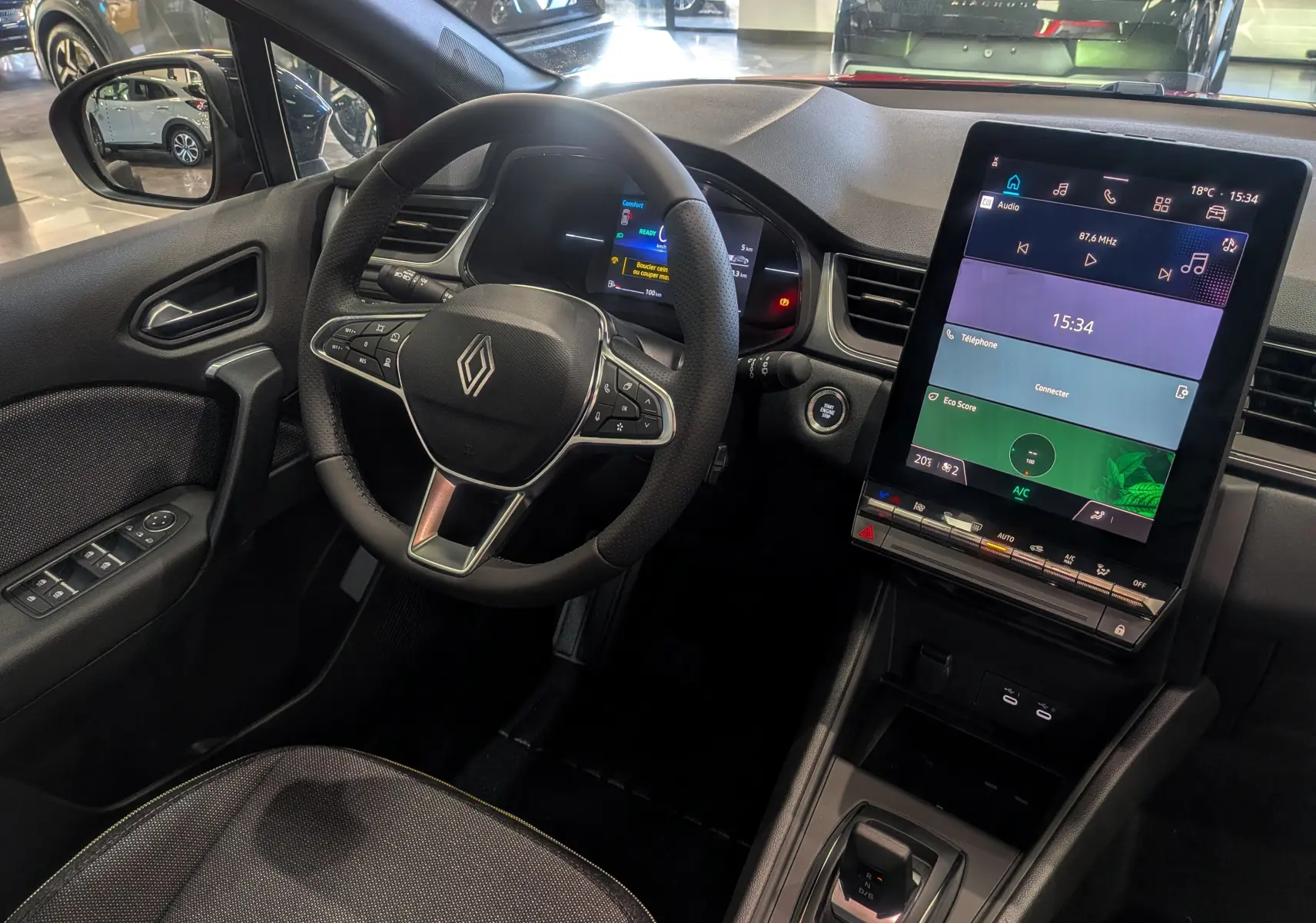 Vue intérieure du poste de conduite du Renault Captur E-TECH 2025, avec volant multifonction et écran tactile vertical.