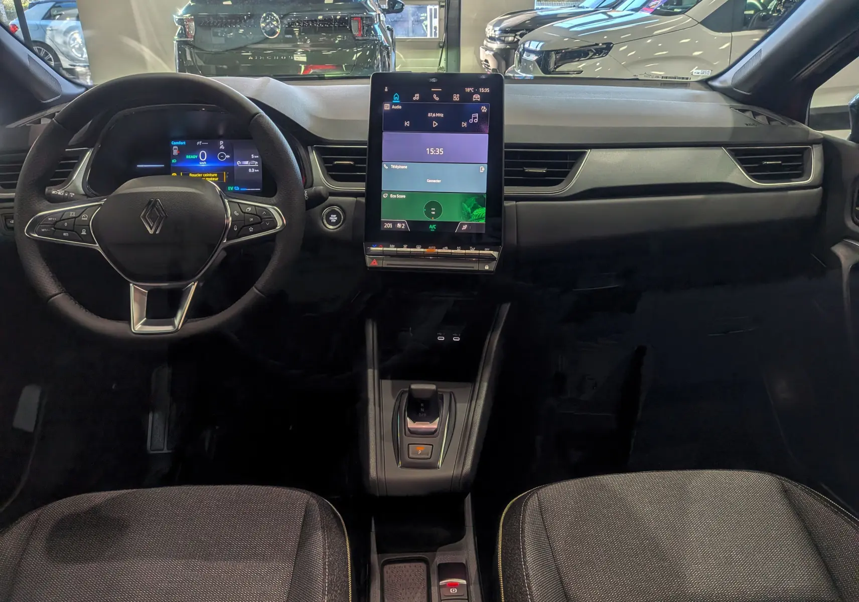 Vue intérieure frontale du tableau de bord du Renault Captur E-Tech 2025 avec écran tactile vertical et volant multifonction.