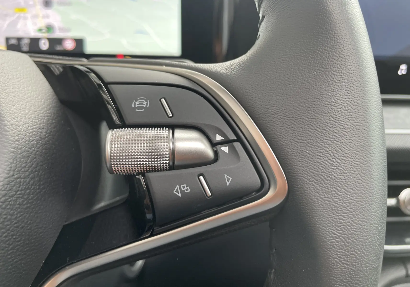 Gros plan sur les commandes multifonctions à gauche du volant cuir noir du Skoda Kodiaq 2024 finition Selection.