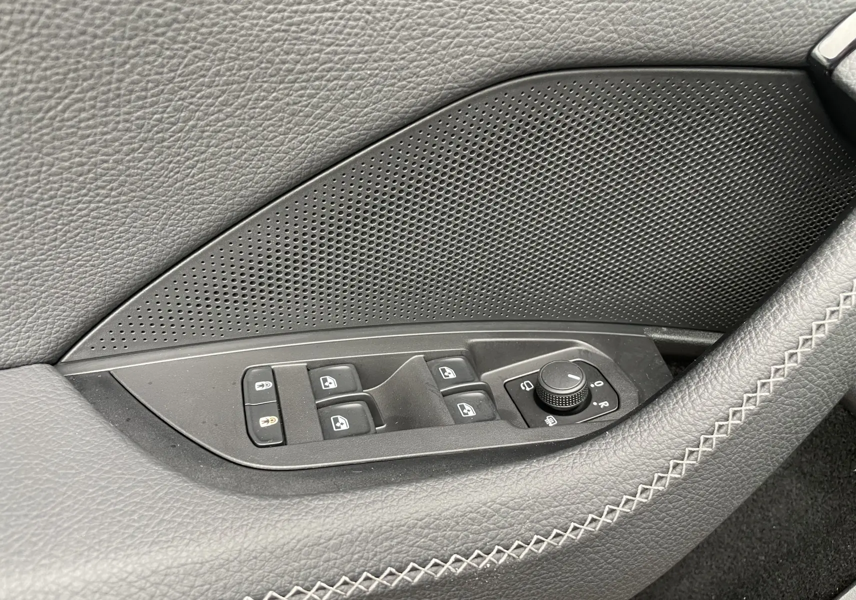 Gros plan sur les commandes de lève-vitres et réglage des rétroviseurs côté conducteur du Skoda Kodiaq noir métal 2024.