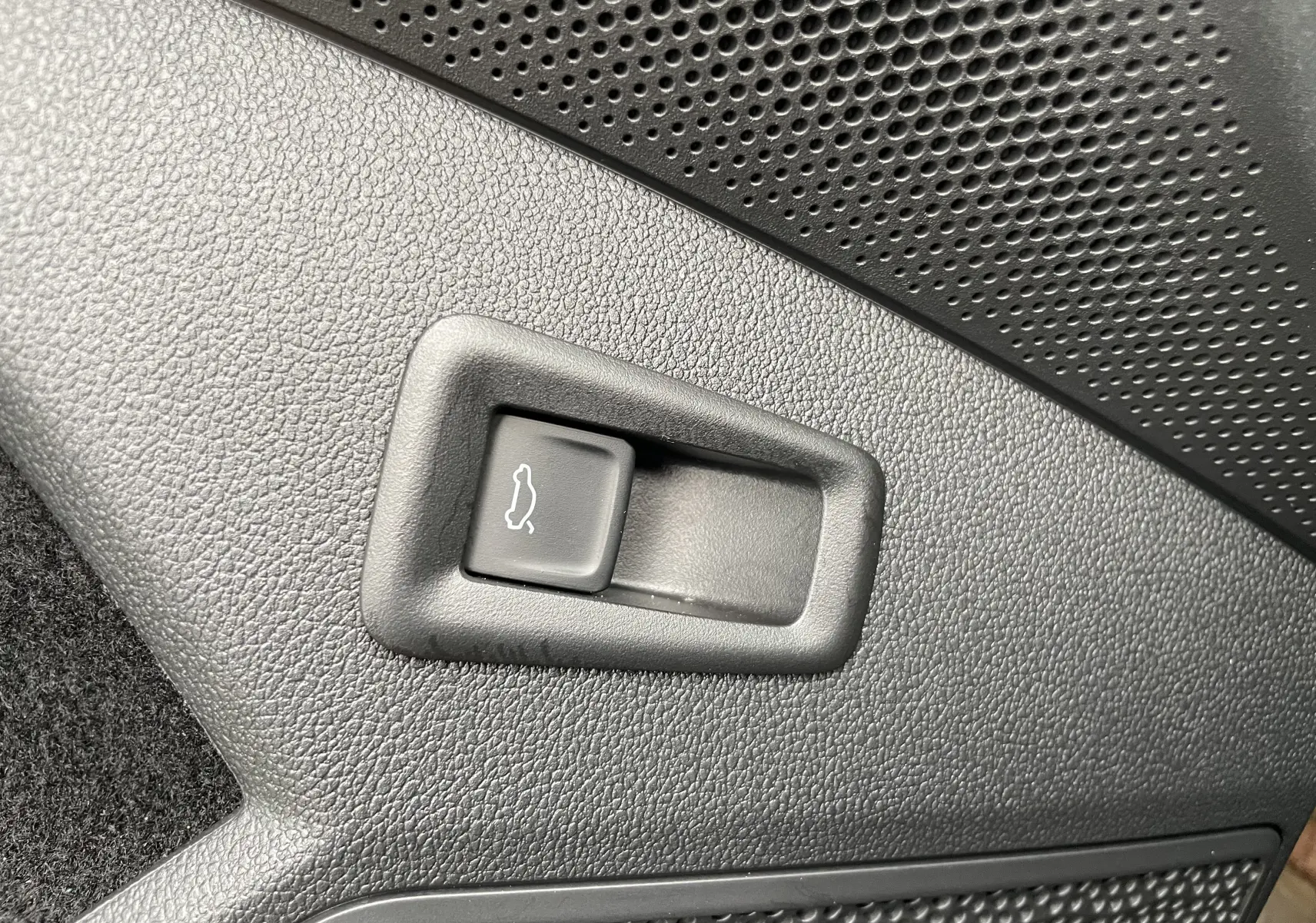 Bouton d'ouverture de coffre intégré dans le panneau intérieur noir texturé d'un Skoda Kodiaq 2024.