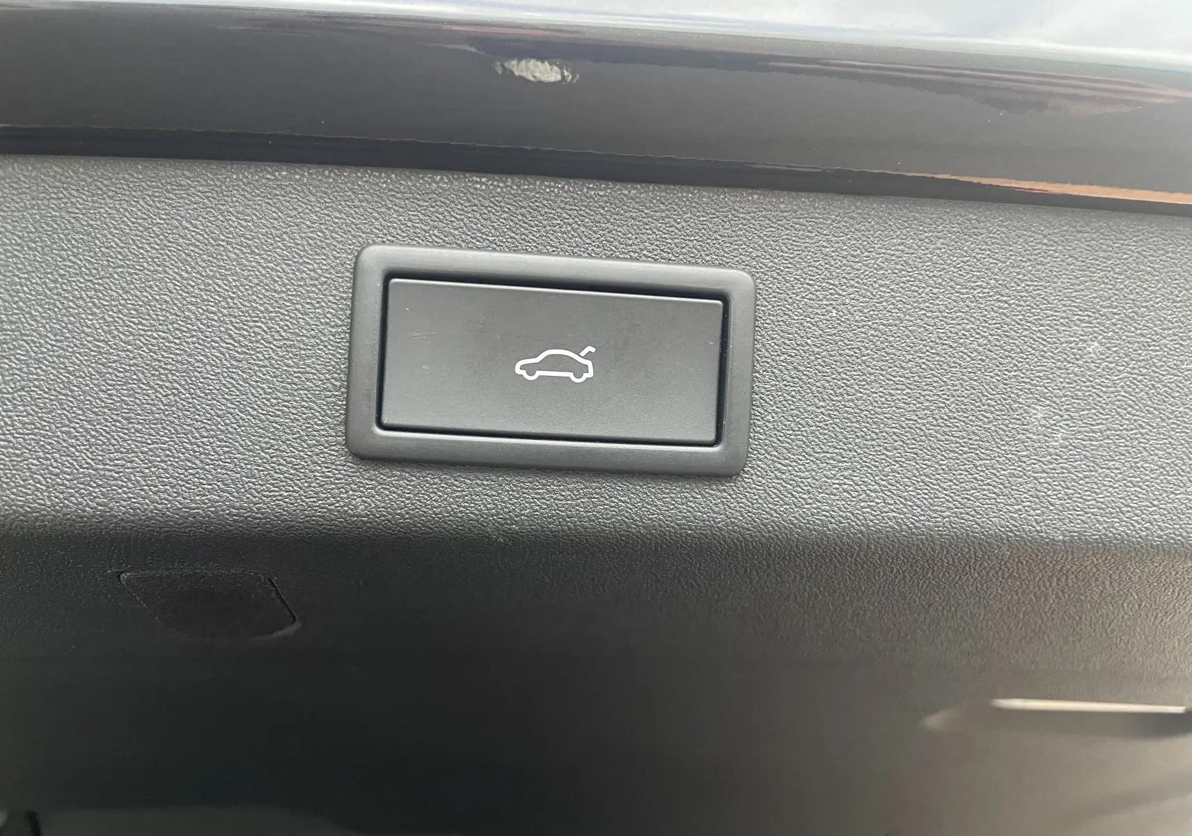 Bouton d'ouverture électrique du hayon sur la garniture intérieure noire du coffre du Skoda Kodiaq 2024.
