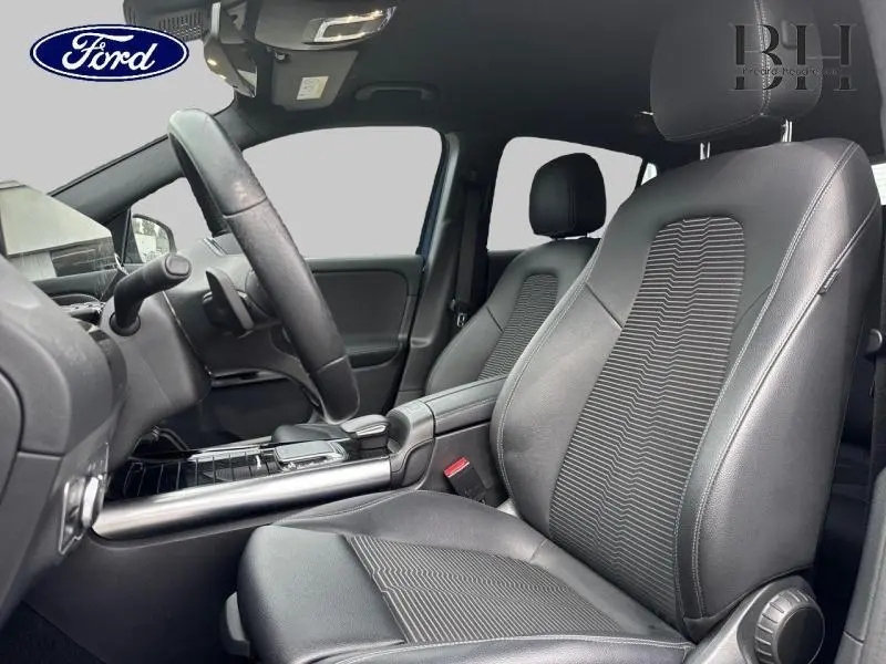 Intérieur avant du Mercedes GLA 250 e bleu denim, sièges en tissu/similicuir ARTICO noir et volant cuir multifonction.