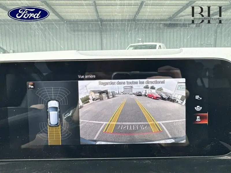 Écran de caméra de recul affichant la vue arrière et le plan de stationnement d’une Mercedes GLA bleu denim métallisé.