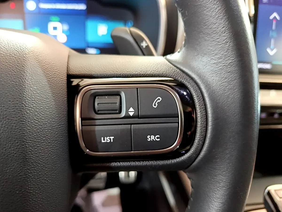 Gros plan sur les commandes gauche du volant cuir noir du Citroën C5 Aircross Hybrid 225 ë-EAT8 Shine Pack.