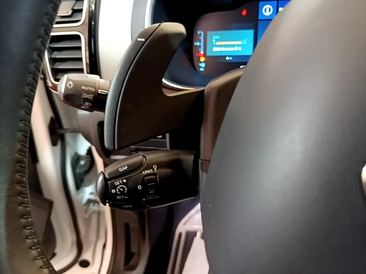 Gros plan sur la commande multifonctions du volant cuir du Citroën C5 Aircross Hybrid blanc, avec affichage numérique en arrière-plan.