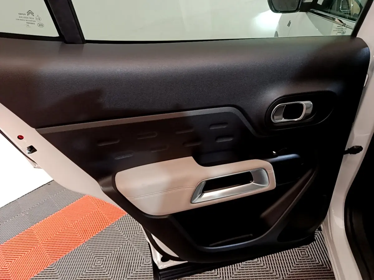 Vue intérieure de la porte arrière droite du Citroën C5 Aircross Hybrid blanc, avec garniture noire et beige.
