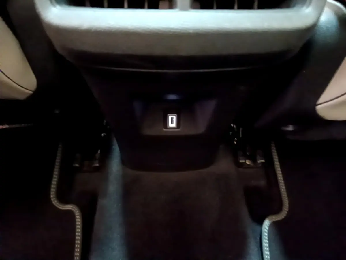 Vue rapprochée de la prise USB arrière entre les sièges noirs et beige du Citroën C5 Aircross Hybrid blanc.