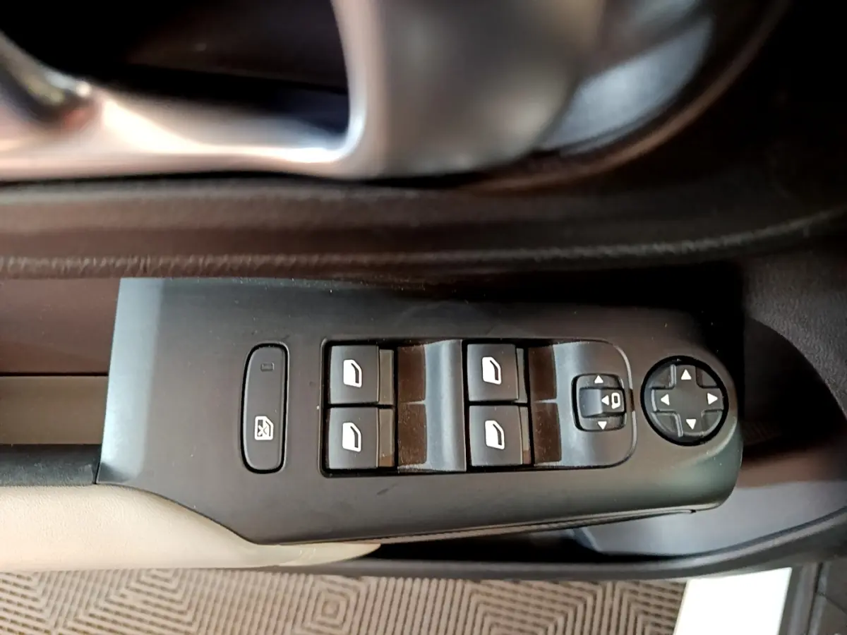 Vue rapprochée des commandes de lève-vitres et rétroviseurs sur la porte intérieure noire et beige d'une Citroën C5 Aircross blanche.