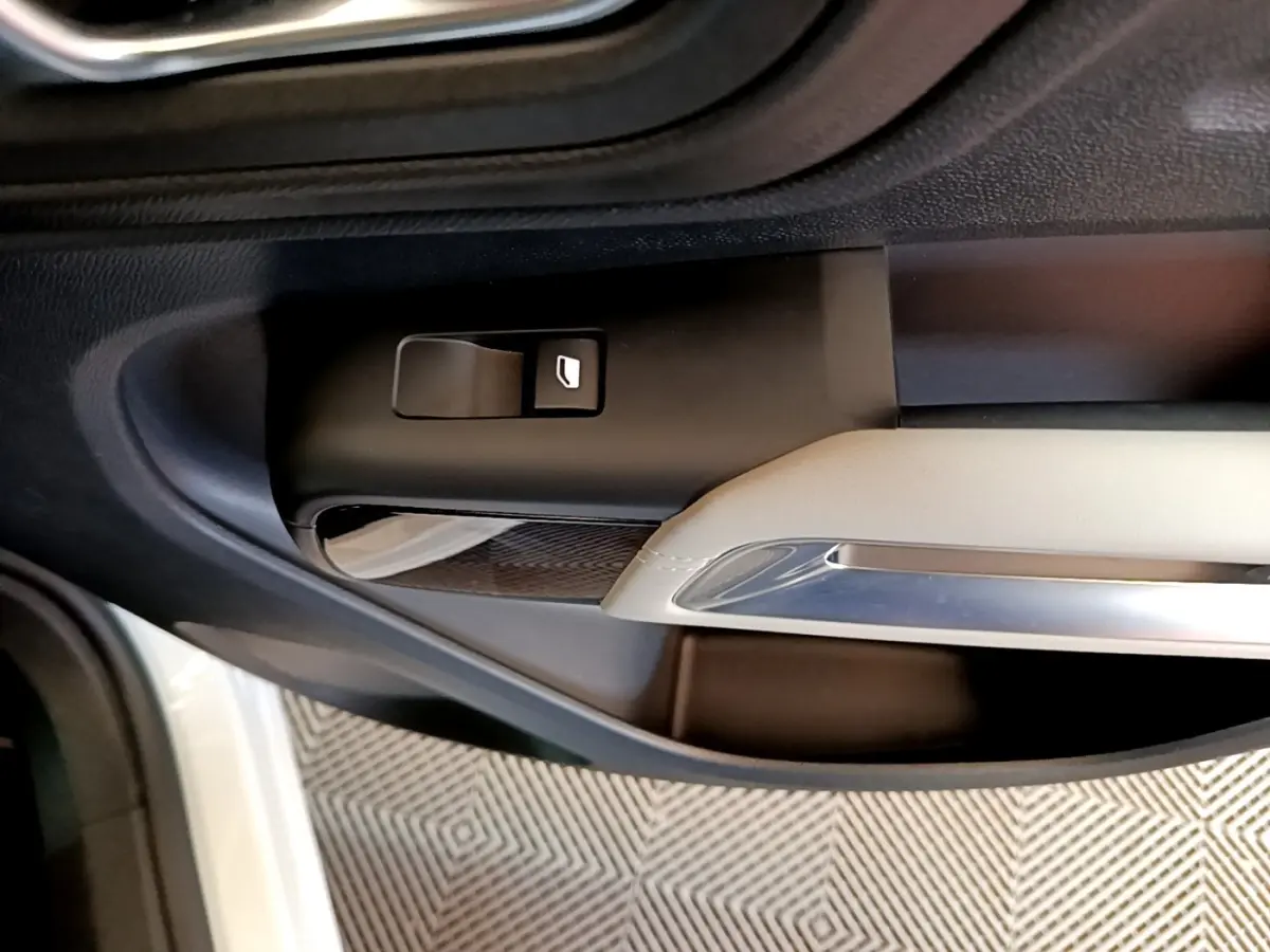 Gros plan sur la commande de lève-vitre côté conducteur de la porte intérieure noire et beige d'un Citroën C5 Aircross blanc.