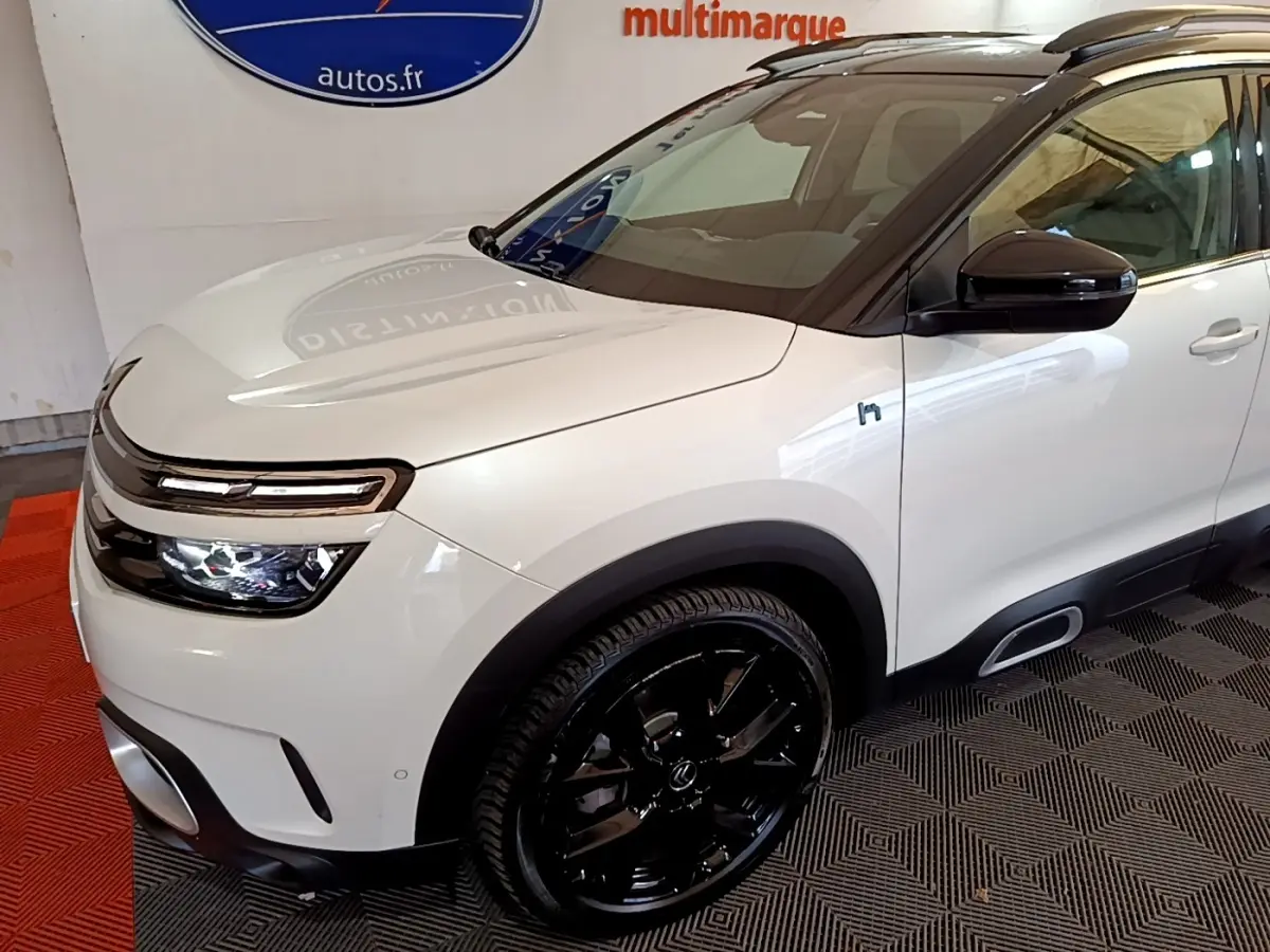 Vue 3/4 avant droit d'un Citroën C5 Aircross Hybrid blanc avec jantes noires et toit noir brillant.