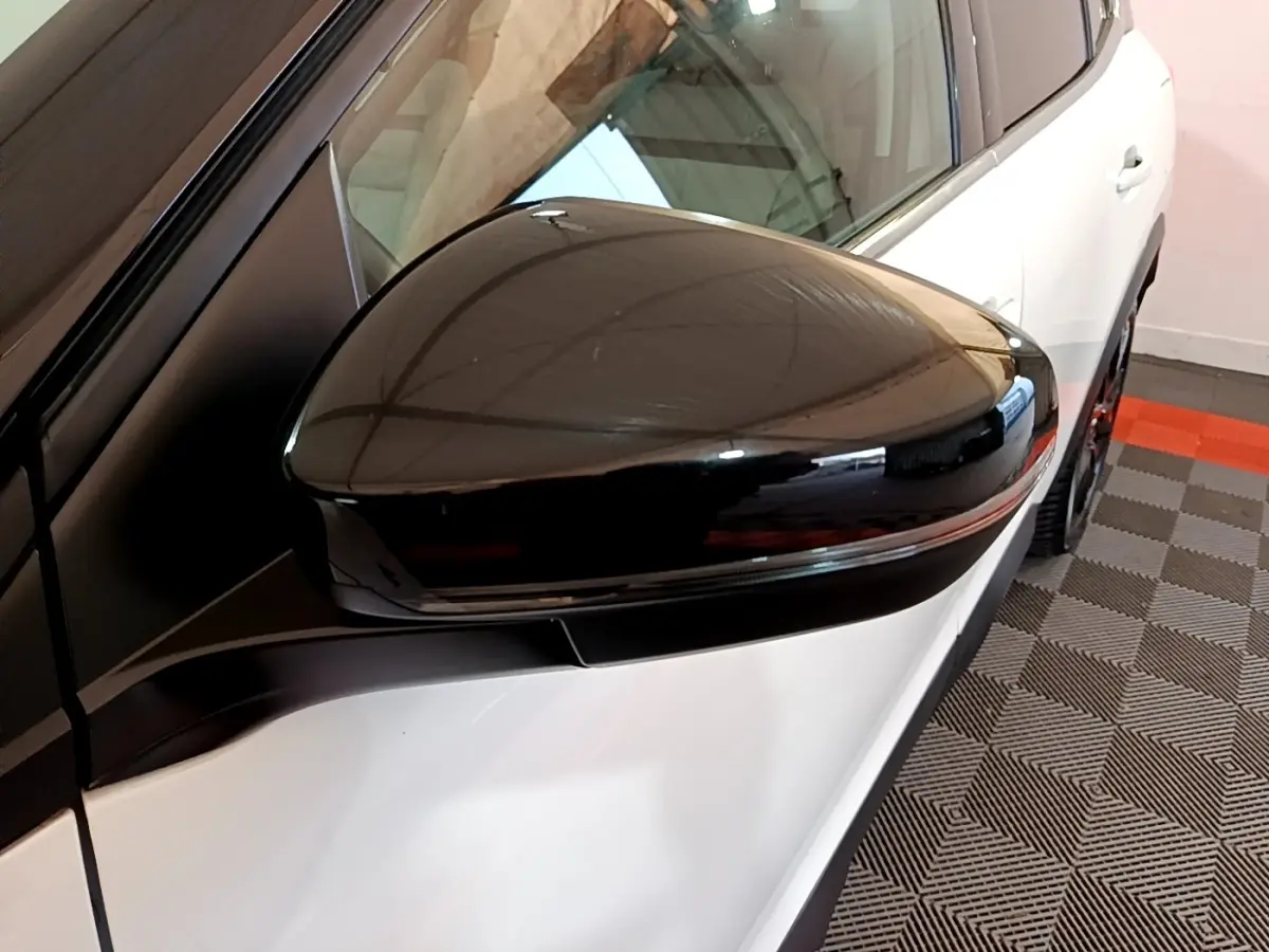 Gros plan sur le rétroviseur noir côté gauche d’un Citroën C5 Aircross Hybrid blanc, avec partie avant visible.