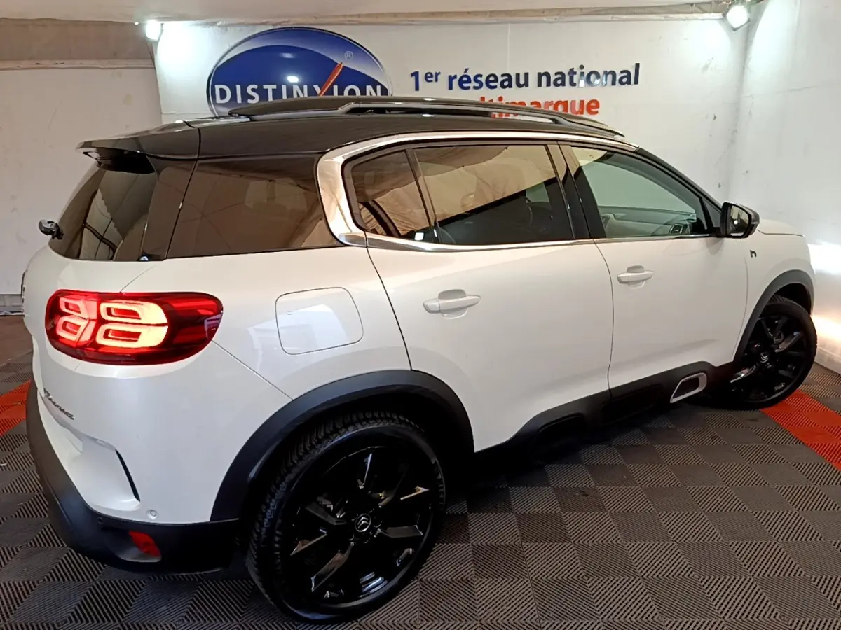Vue 3/4 arrière droite du Citroën C5 Aircross Hybrid blanc avec toit noir et jantes noires brillantes.