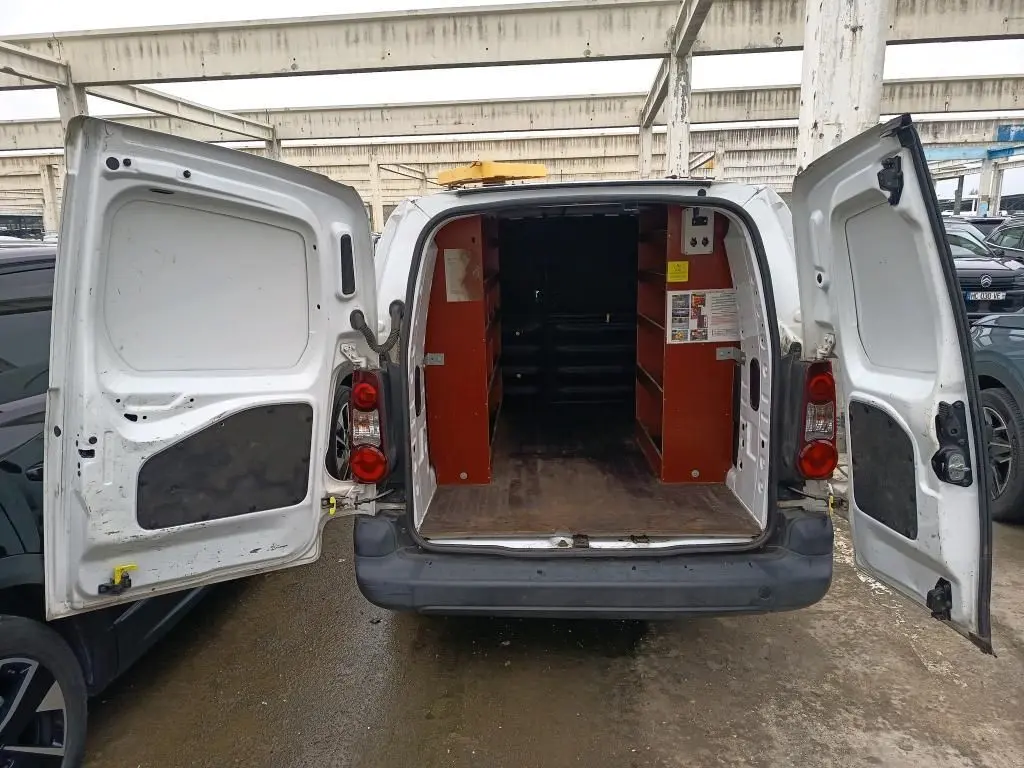 Vue arrière d’un Citroën Berlingo XL blanc 2018 avec portes ouvertes montrant l’intérieur utilitaire aménagé et un gyrophare jaune sur le toit.
