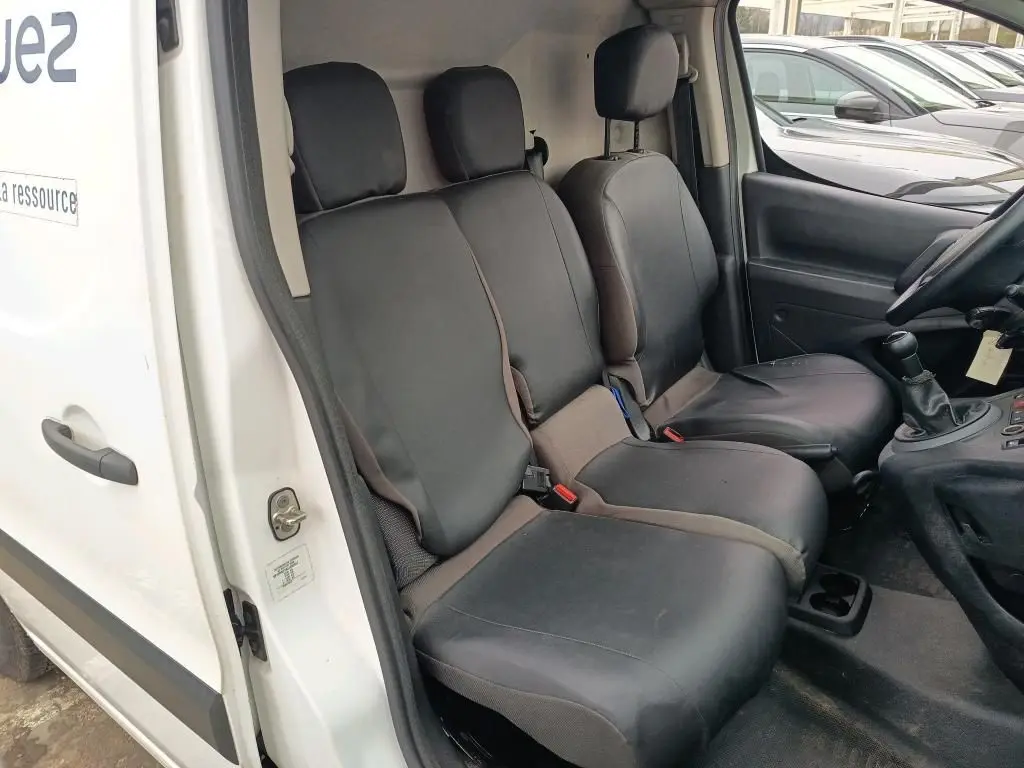 Vue intérieure côté conducteur du Citroën Berlingo blanc 2018, montrant les sièges avant en tissu noir et la boîte manuelle.