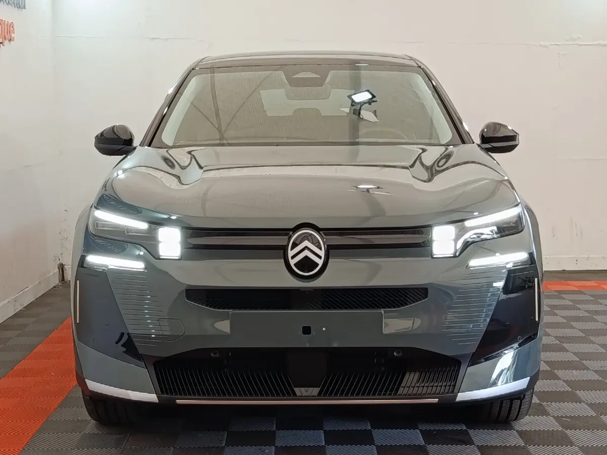 Vue frontale d'une Citroën C5 hybride 145ch auto MAX verte avec feux LED allumés dans un garage.
