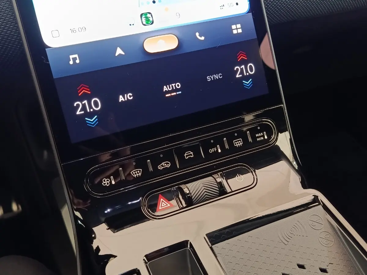 Gros plan sur la console centrale tactile noire du Citroën C5 Hybride 2026 avec commandes climatisation et recharge sans fil.