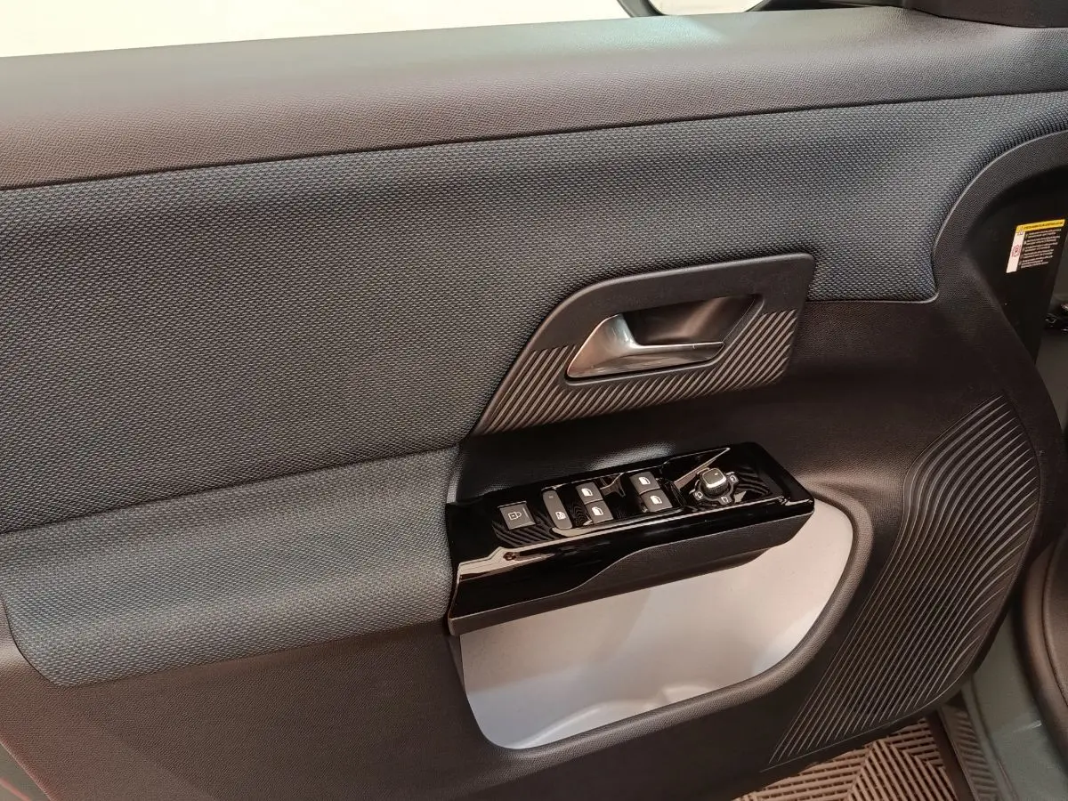 Gros plan sur la porte intérieure côté gauche de la Citroën C5 Hybride 2026, avec commandes de vitres et poignée noire.