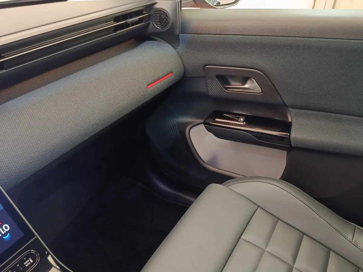 Vue intérieure côté passager avant du Citroën C5 Hybride 2026, avec sellerie grise et garnitures noires texturées.