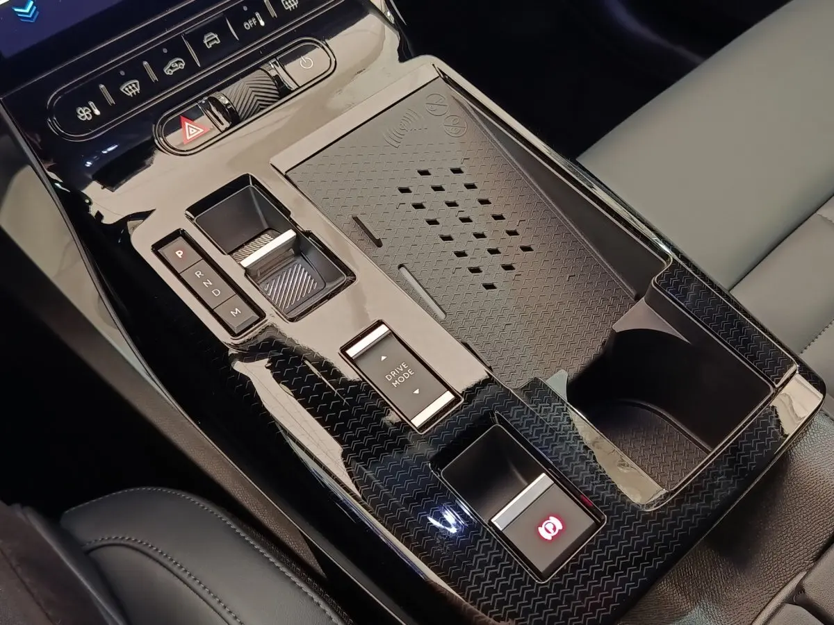 Gros plan sur la console centrale noire brillante de la Citroën C5 hybride avec commandes de boîte auto et recharge sans fil.