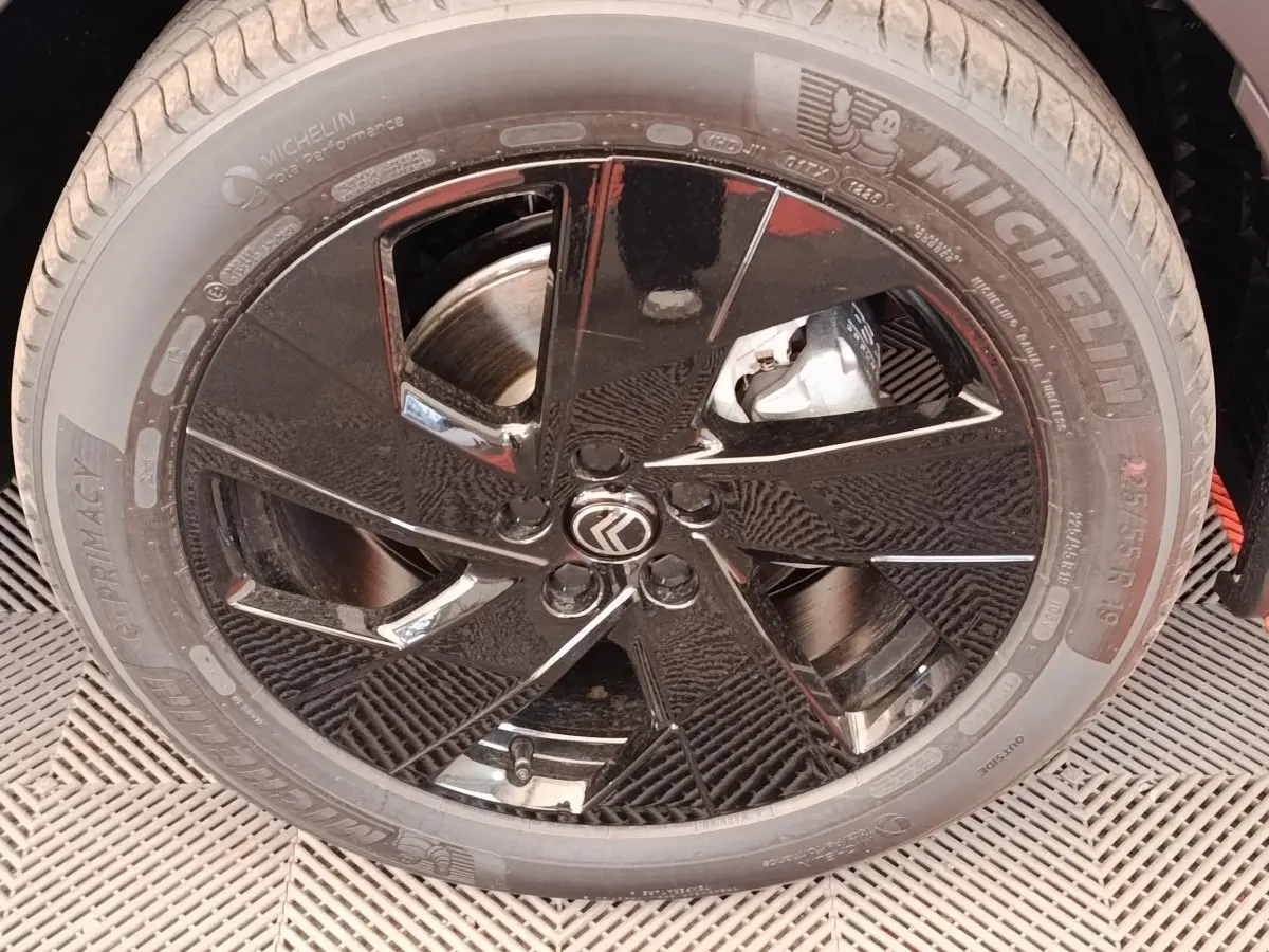 Gros plan sur la jante noire brillante de 19 pouces avec logo Citroën et pneu Michelin sur C5 hybride vert.