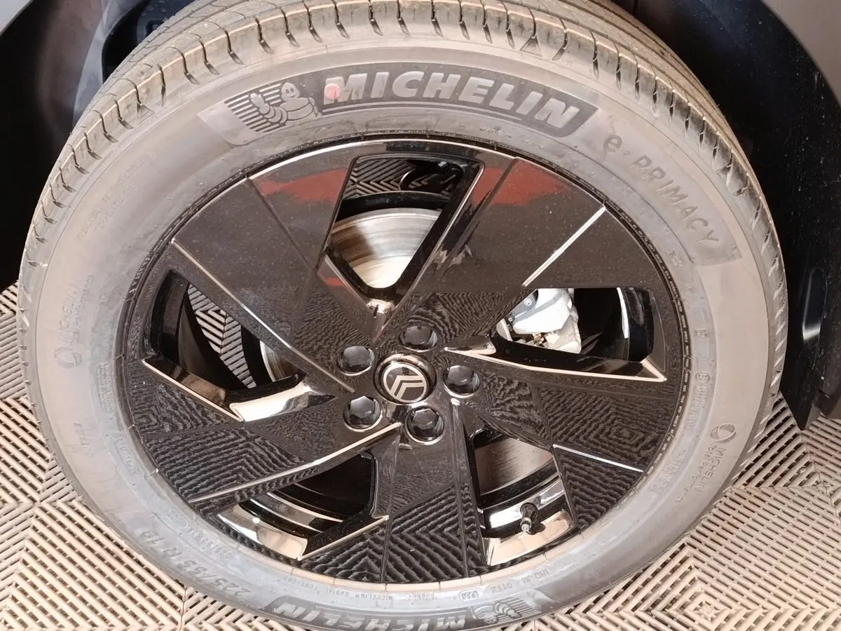 Gros plan sur la roue avant droite avec jante noire brillante et pneu Michelin sur Citroën C5 hybride vert.