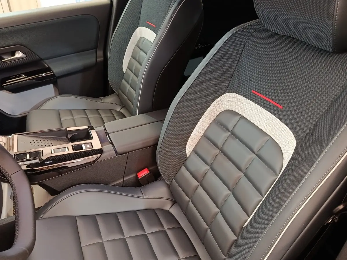 Vue intérieure rapprochée des sièges avant gris et noir avec surpiqûres et accoudoir central de la Citroën C5 Hybride 2026.