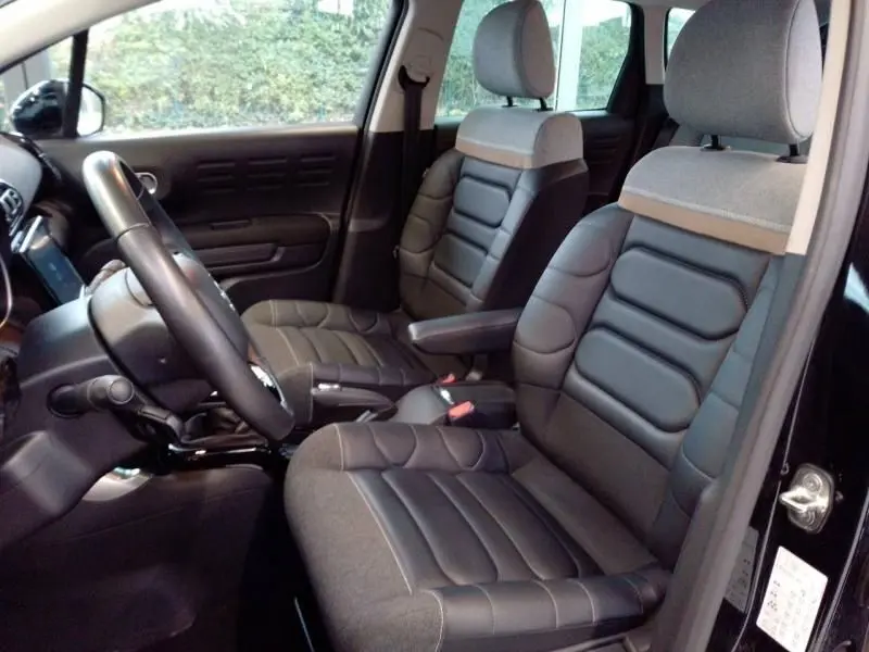 Vue intérieure côté conducteur du Citroën C3 Aircross 2022 noir, sièges en tissu et cuir bicolore avec accoudoir central.