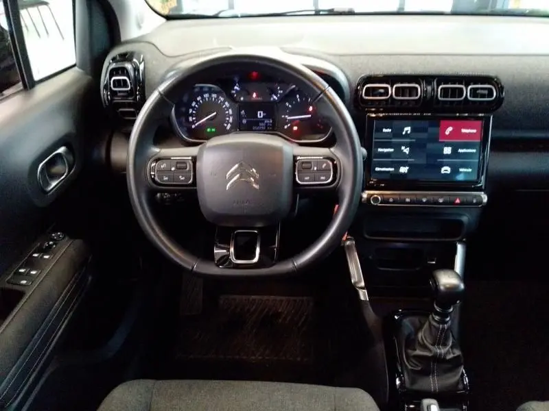 Vue intérieure centrée sur le volant et tableau de bord du Citroën C3 Aircross noir avec écran tactile et boîte manuelle.