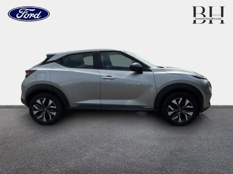 Profil droit d'un Nissan Juke gris perle métallisé 2023 avec jantes noires et détails noirs contrastants.