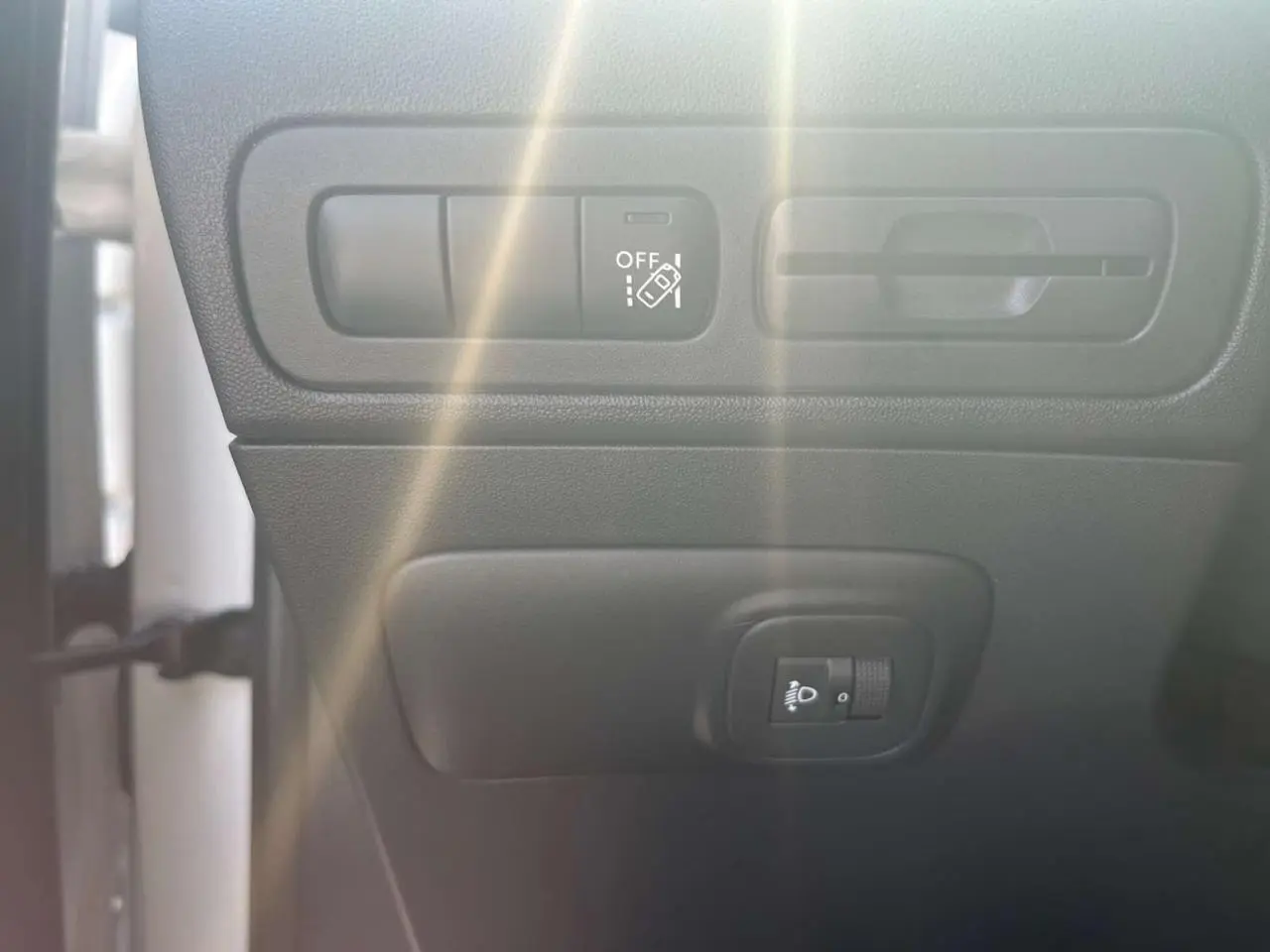 Détail des commandes d'aide à la conduite et réglage des phares dans l'habitacle du Citroën C3 Aircross blanc banquise.