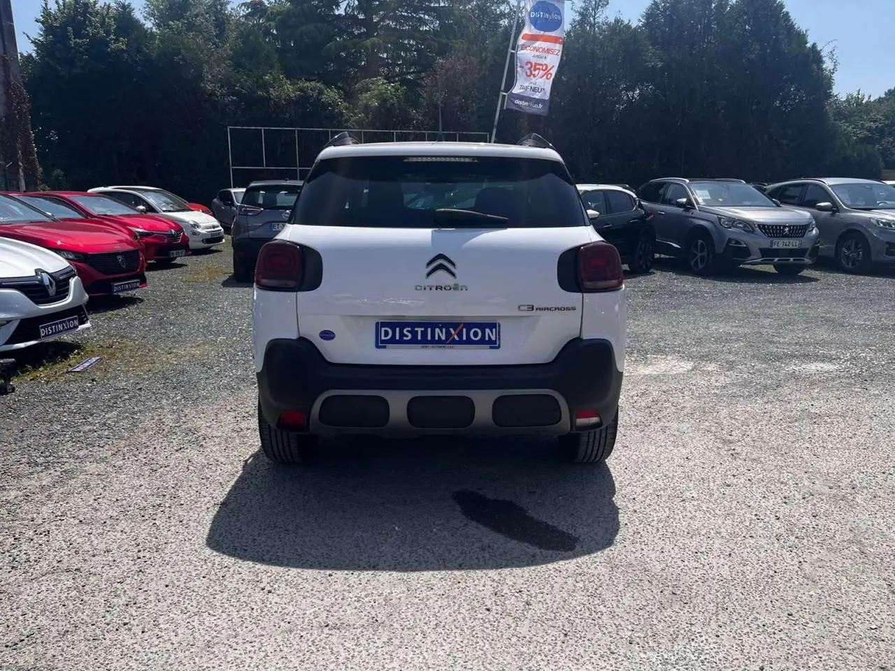 Vue arrière d'un Citroën C3 Aircross blanc Banquise avec barres de toit et feux arrière foncés sur parking.