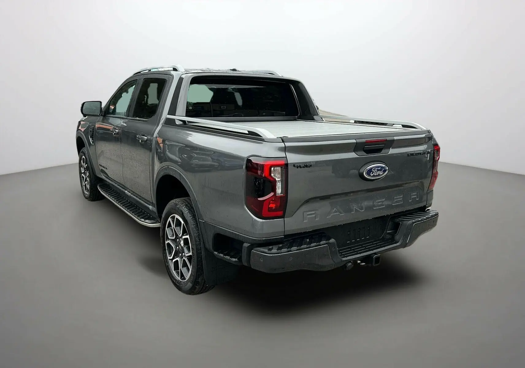 Ford Ranger 3.0 V6 240 Wildtrak Plus gris carbone vu en 3/4 arrière droit avec benne couverte et jantes spécifiques.